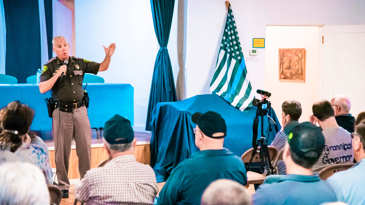 Sheriff Rob Snaza uses a microphone to address the crowd at the Adna Grange Hall last August on the topic of police reform.